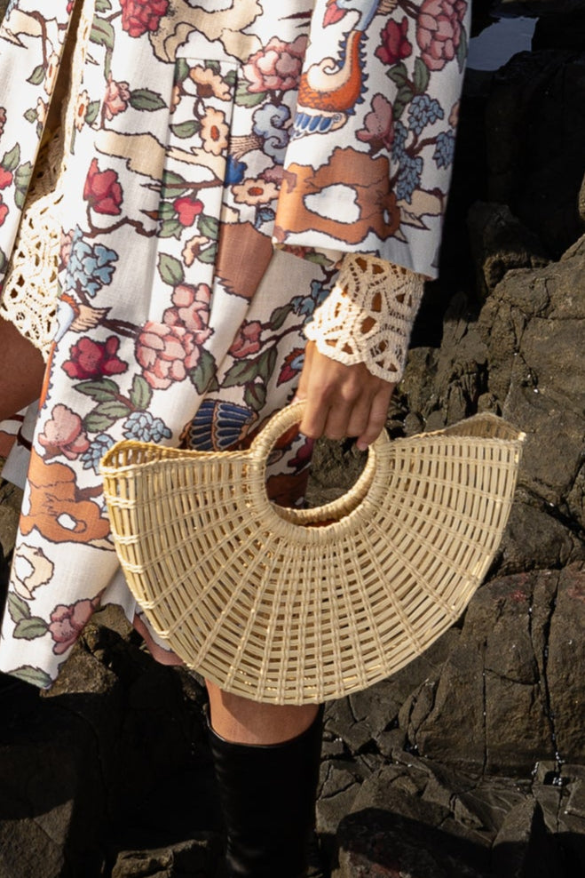 Close-up of model in floral attire holding the Sailor Moon Tote, highlighting the elegance and handcrafted finish of the straw bag.