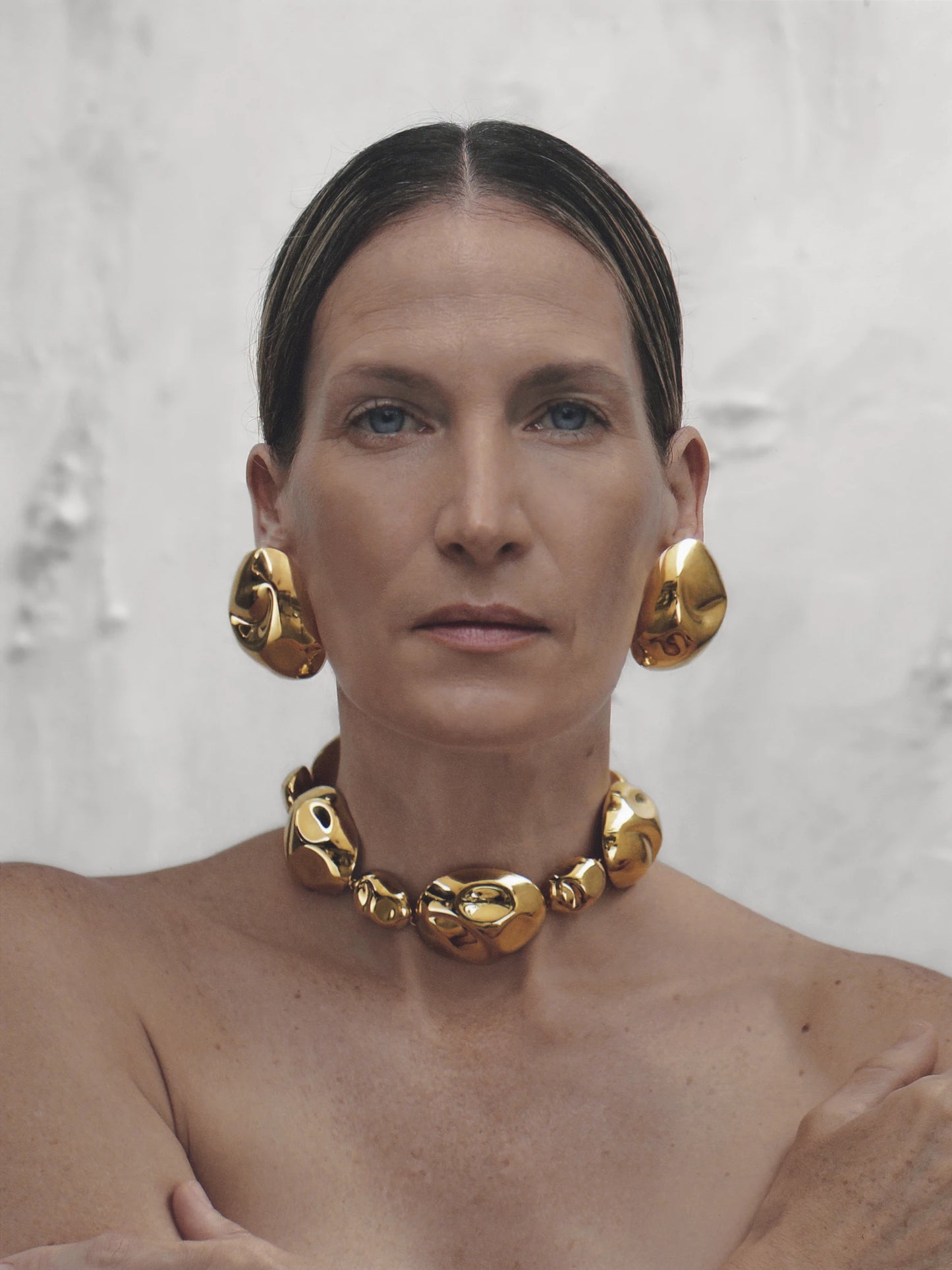 Light-skinned model posing with the chunky gold-plated necklace and matching earrings, showcasing its elegant and powerful presence.