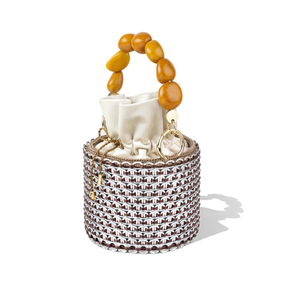 Side profile of the Alex Bucket Bag showing off its cylindrical form, golden beaded handle, and semi-transparent lattice detailing.