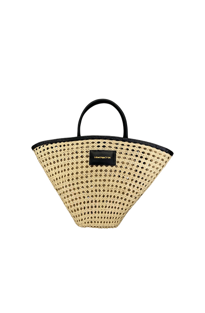 Front-facing image of the Seashell Tote, handwoven in natural toquilla straw with a structured black eco-leather trim and top handles.