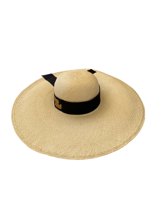 Angled top-down view of the Luna Hat by My Paloma, crafted from fine handwoven straw with a wide, structured brim and finished with a black grosgrain ribbon featuring the signature gold dove motif.