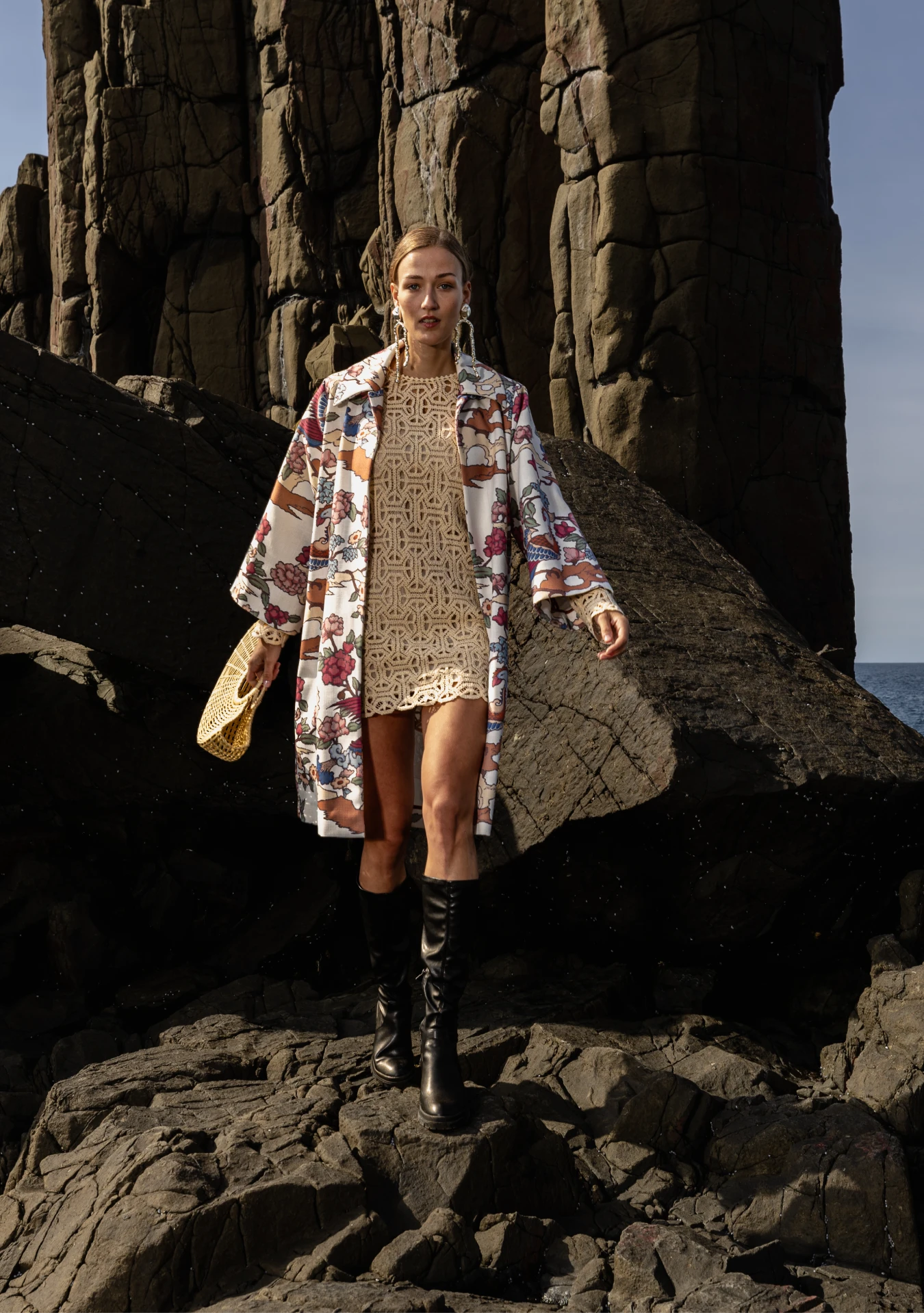 Girl wearing the Phoenix Kimono with peach and green bird motifs, photographed in the rocky shores Lisbon, Portugal – cultural craftsmanship by My Paloma.

