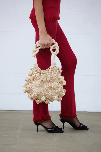 Cream Ameba Mesh Bag styled with bold red pants and heels, captured mid-stride in an urban location, Lima, Peru.