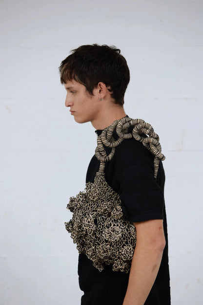 Male model in minimalist black tee holding the black Ameba Mesh Bag over shoulder, in a studio set-up inspired by Melbourne streetwear styling.
