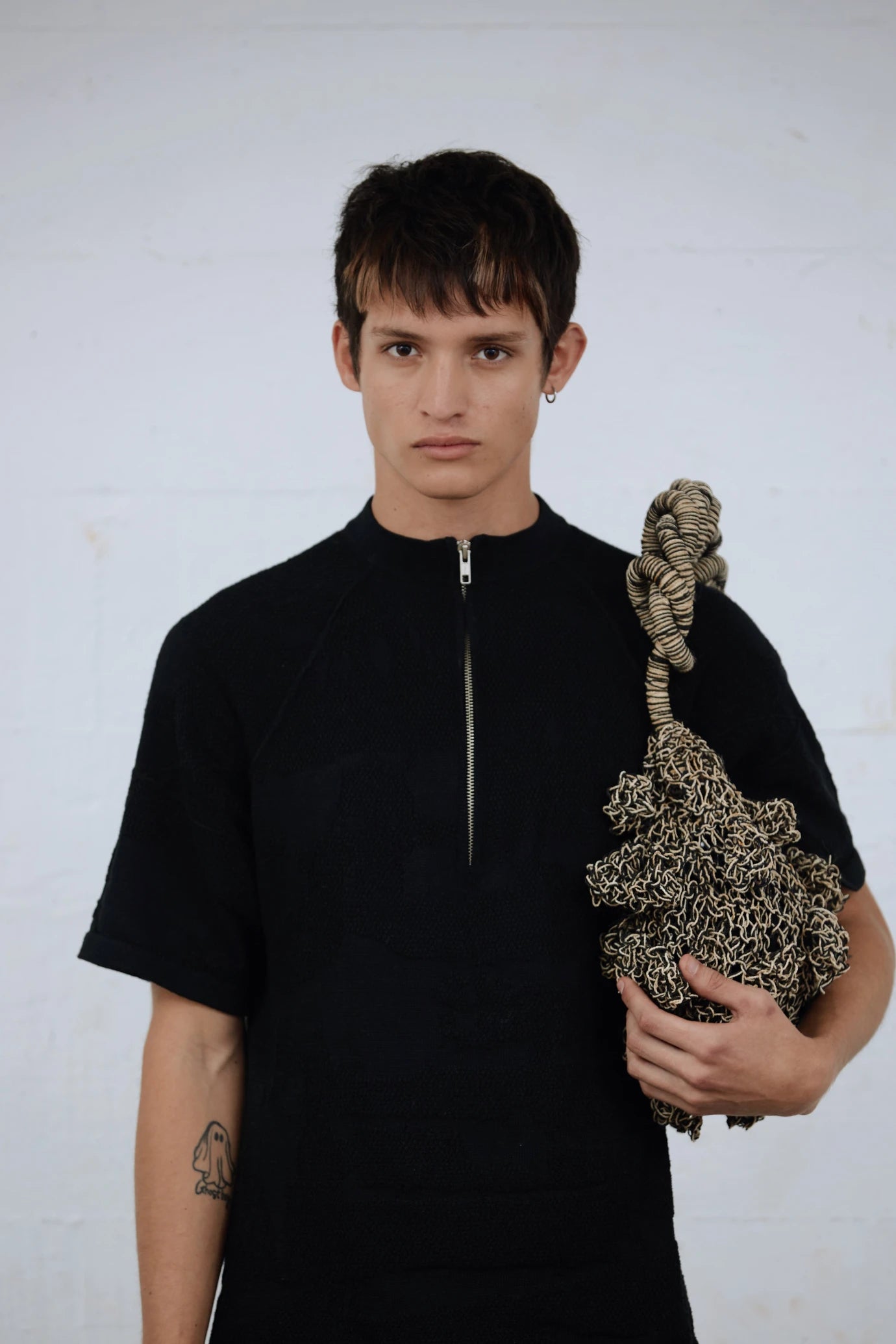 Profile view of male model wearing the Ameba Mesh Bag in neutral tone, representing gender-inclusive accessory styling.