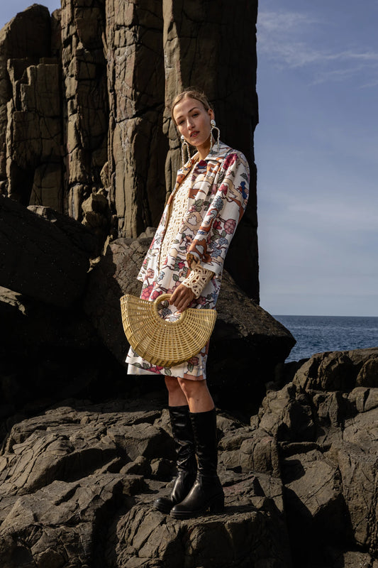 Model standing on volcanic rock formations, holding the Sailor Moon Tote—its architectural shape and artisanal detail contrasting against the rugged backdrop.