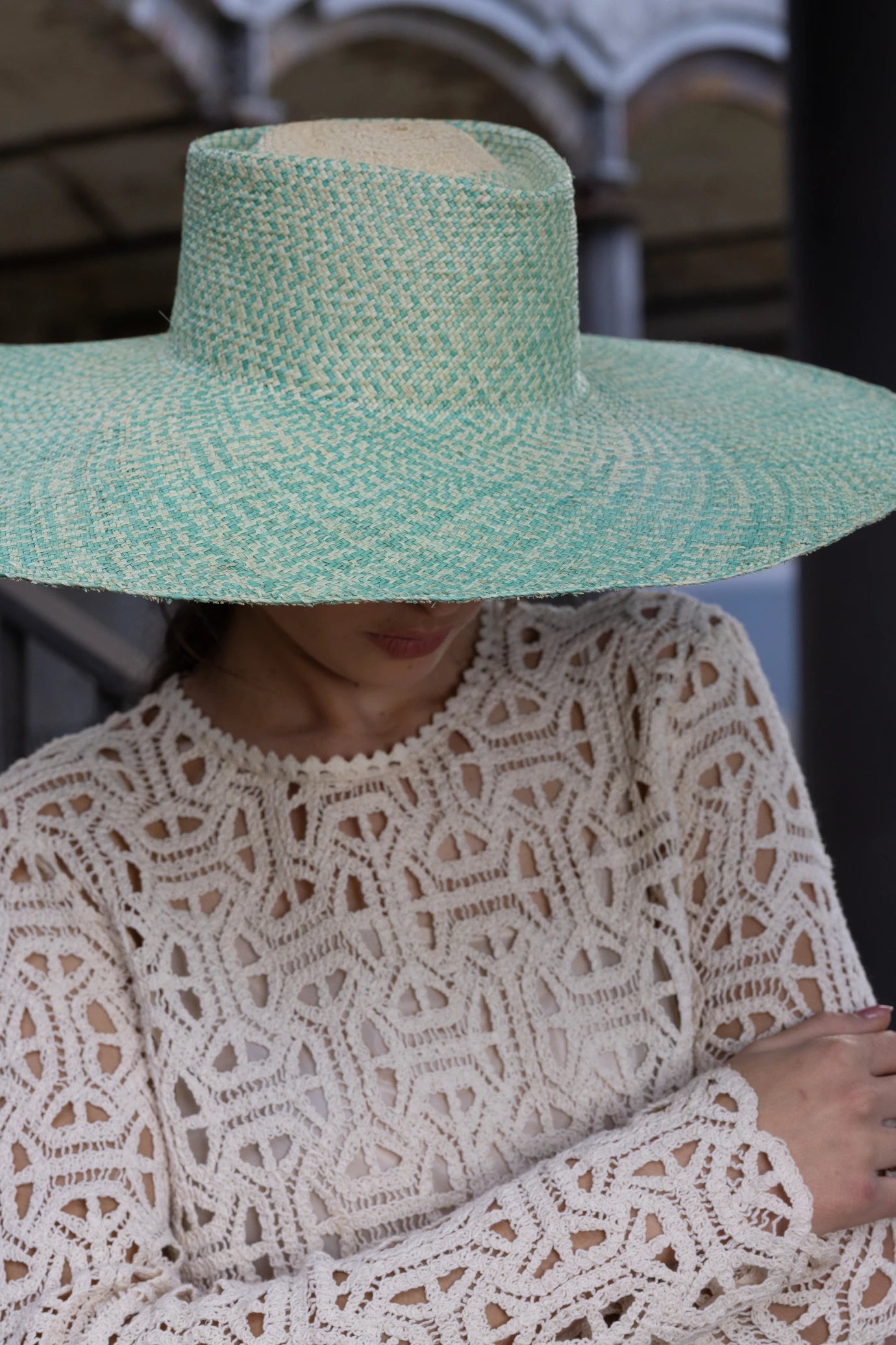 Model wearing the Chalan Sunhat pulled low over the face, casting a natural shadow over her crochet outfit—emphasising the hat’s structured silhouette and sun-shielding brim.