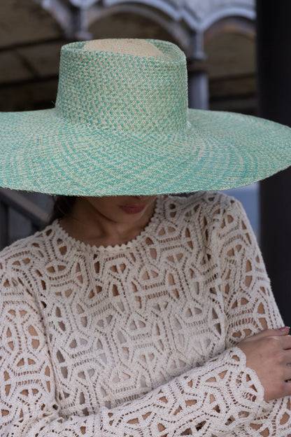 Model wearing the Chalan Sunhat pulled low over the face, casting a natural shadow over her crochet outfit—emphasising the hat’s structured silhouette and sun-shielding brim.