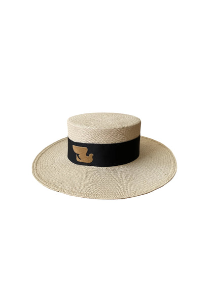 Front-angled product image of the Wayra Hat featuring a flat crown and wide brim, finished with a thick black ribbon and embroidered dove motif—crafted from natural straw for structured luxury.