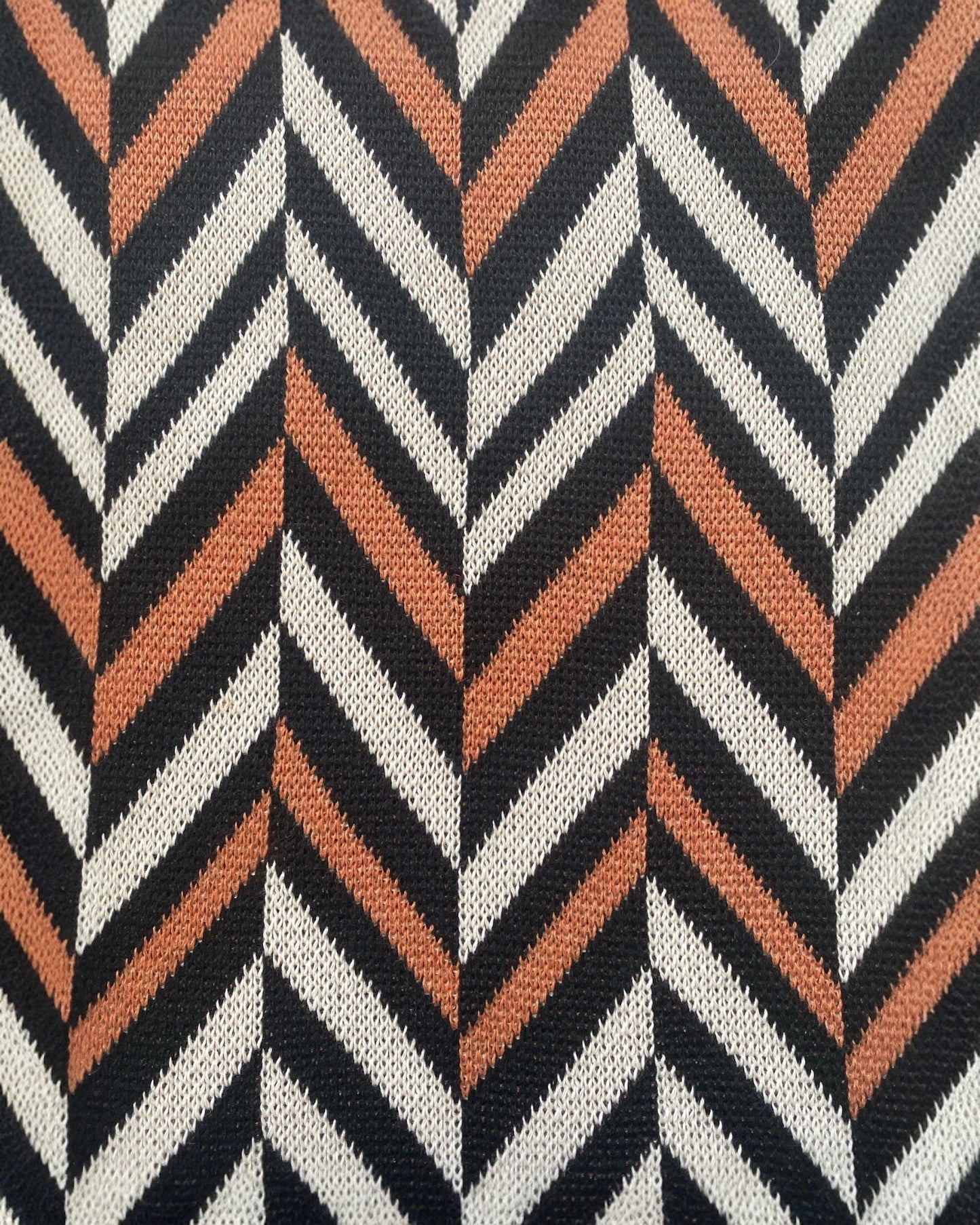 Detailed close-up of the My Paloma Zig Zag knit fabric, featuring bold chevron stripes in black, ivory, and terracotta orange, highlighting premium weave and graphic pattern texture.