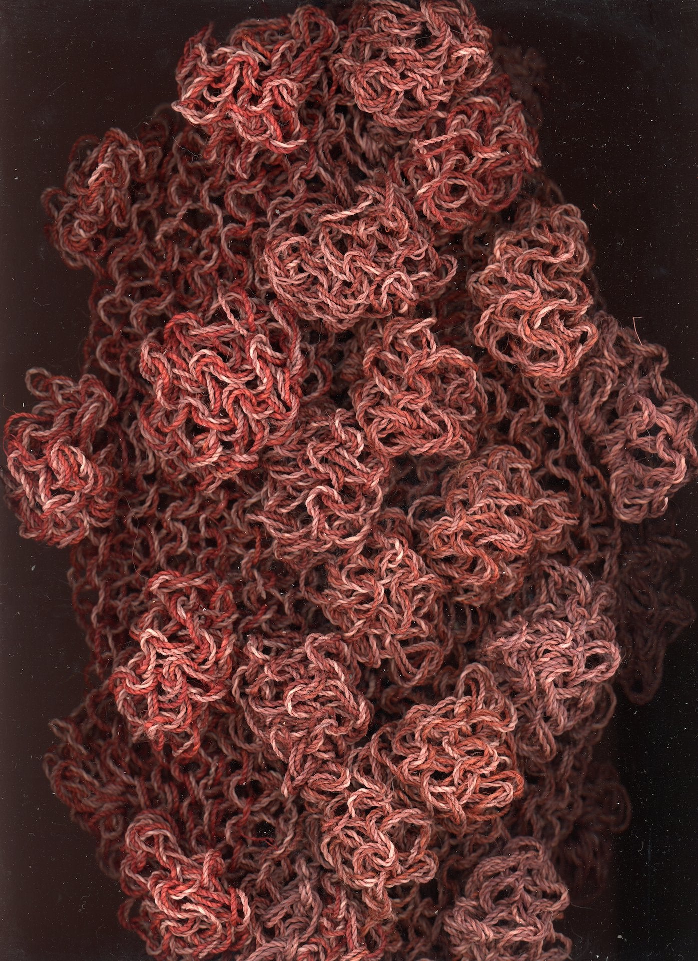 Macro close-up of the crochet craftsmanship on the burgundy Ameba Mesh Bag, showing intricate looping and texture.

